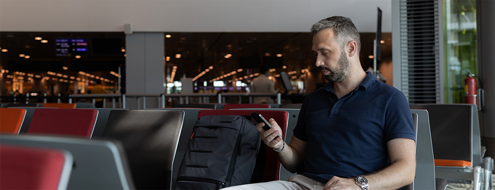 Image of man streaming from his phone while seated in the waiting area of an airport